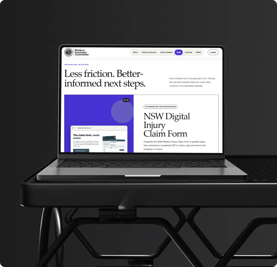A laptop on a stand showing the Workers Insurance Association tools page, with the digital injury claim form initiative open.